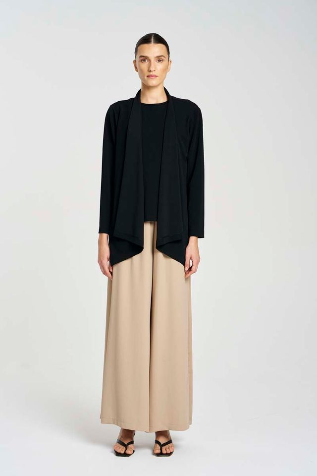 Person wearing a black top and beige pants on a white background