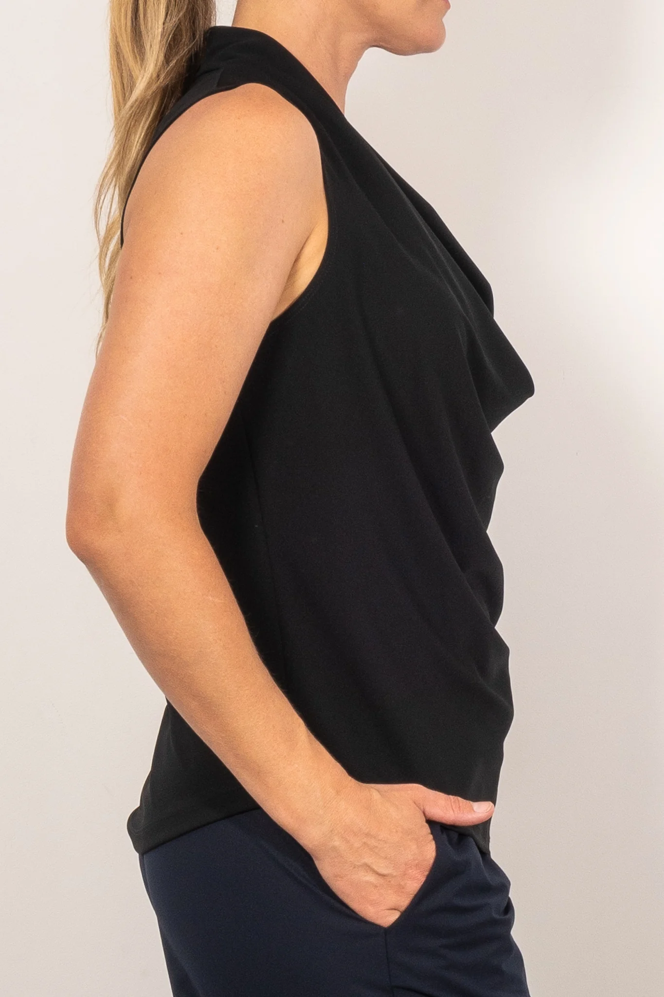 Woman wearing a black sleeveless top against a plain background