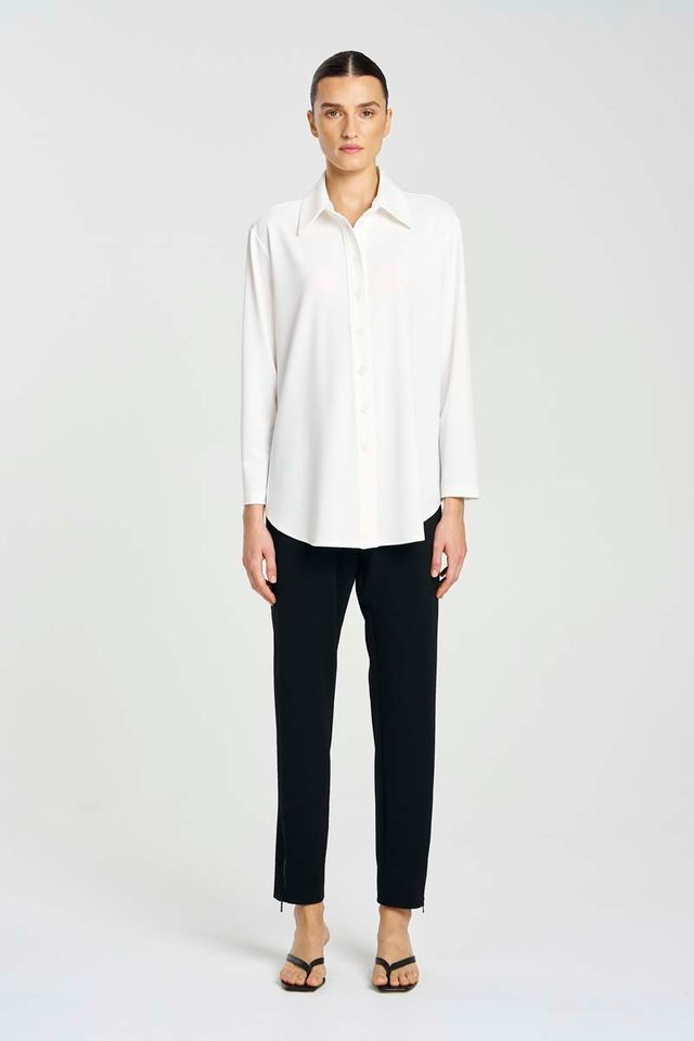Person wearing a white blouse and black pants on a white background