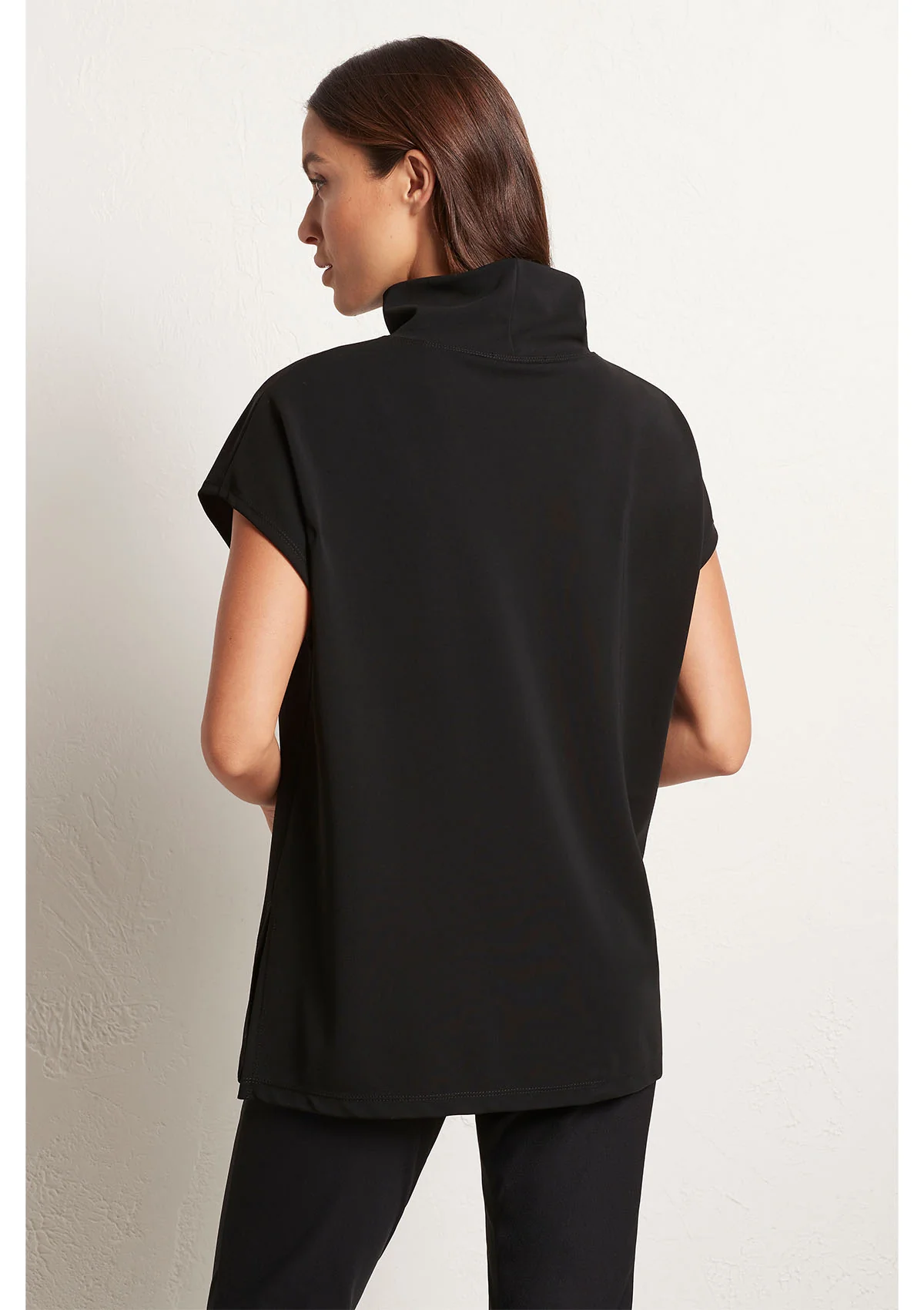 Woman wearing a black sleeveless top against a plain background