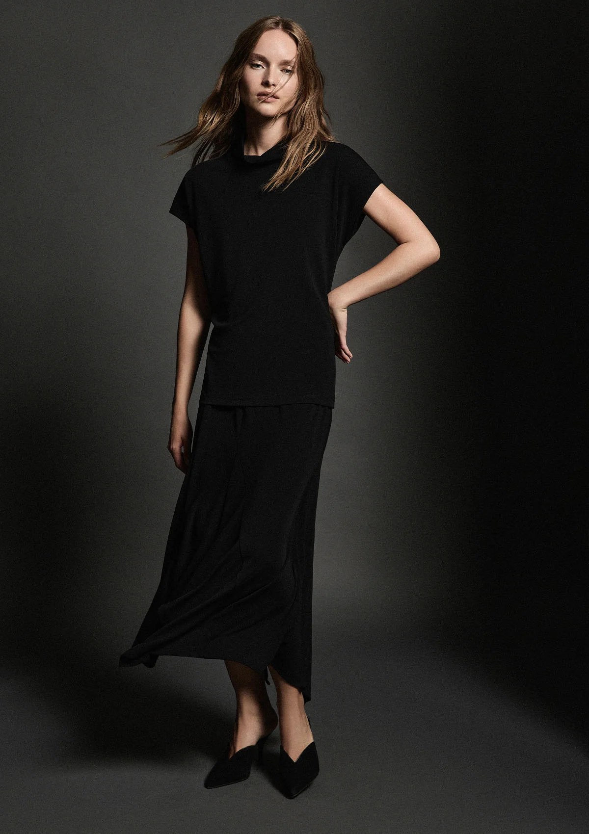 Woman wearing a black outfit against a dark background