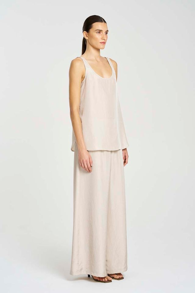 Woman wearing a light pink sleeveless top and long skirt on a white background