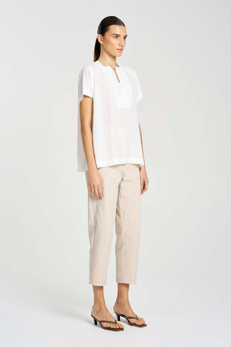 Woman wearing a white blouse and beige pants on a white background