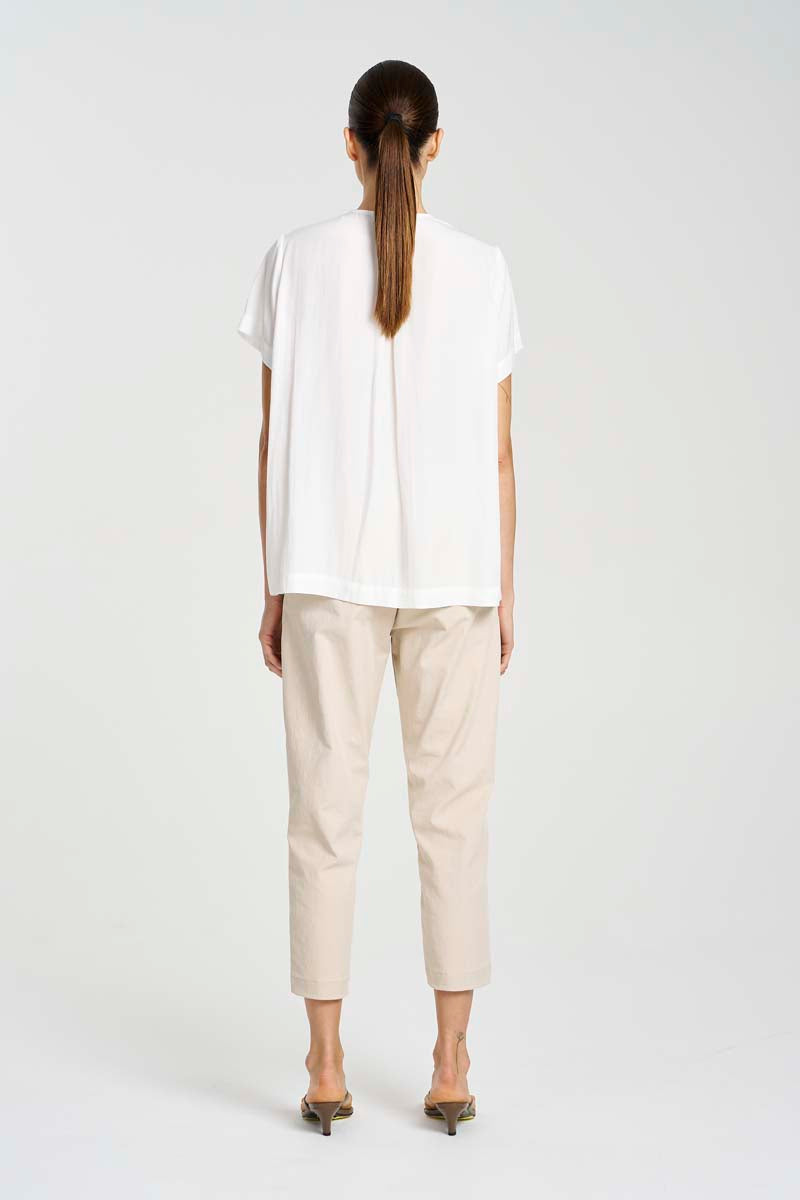 Person wearing a white top and beige pants on a white background