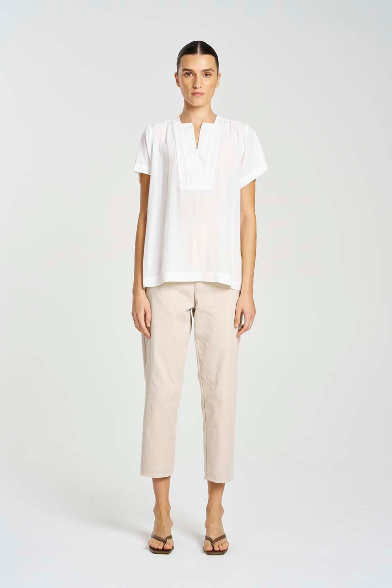 Person wearing a white blouse and beige pants on a white background