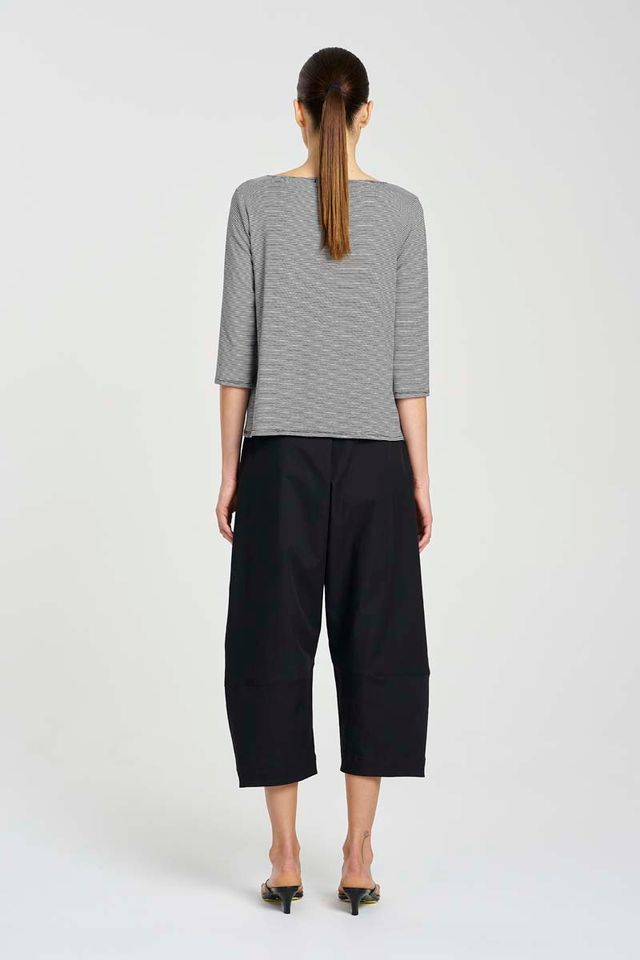 Person wearing a gray striped shirt and black pants on a white background