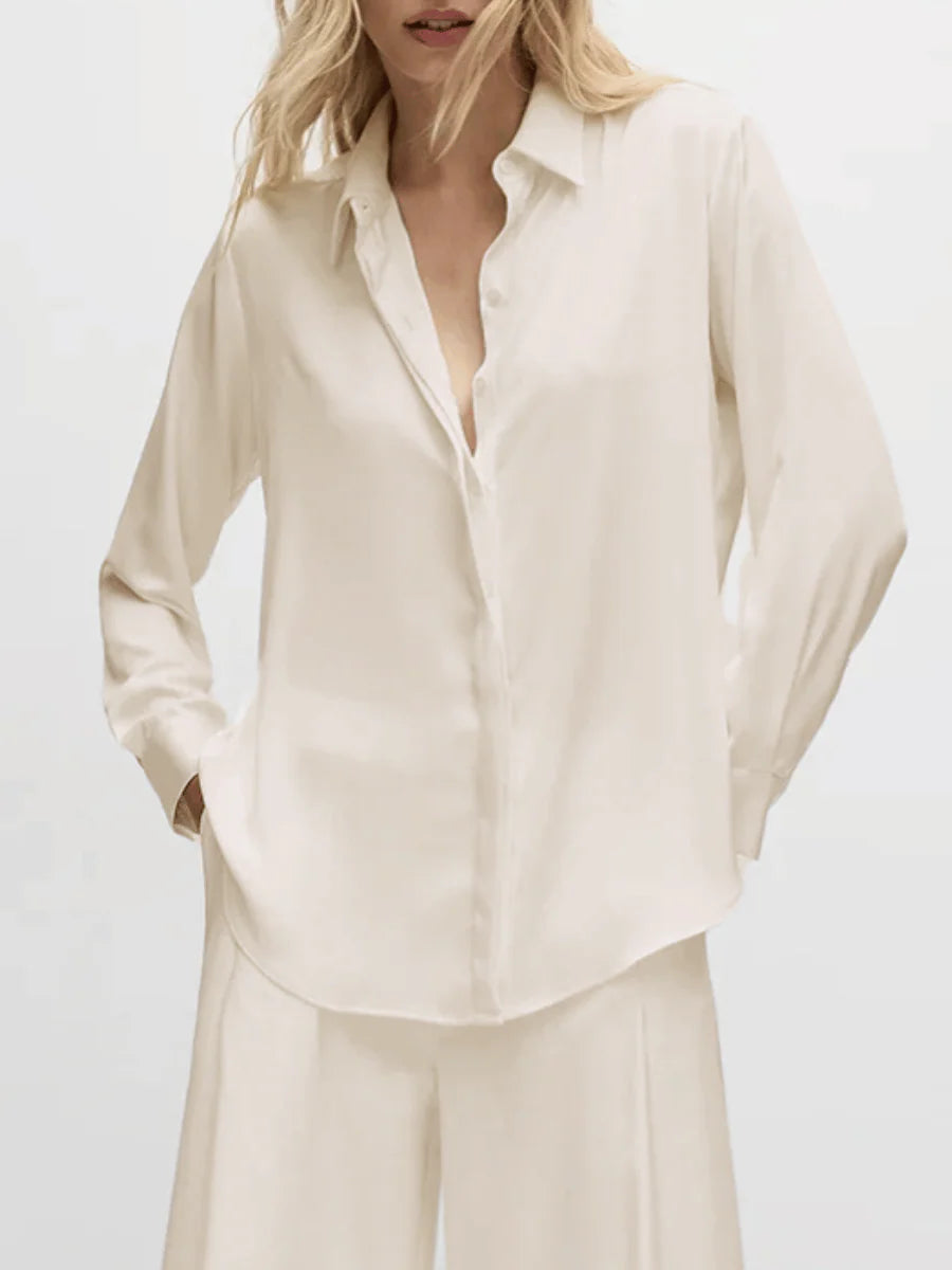 Person wearing a light beige button-up shirt and pants on a white background