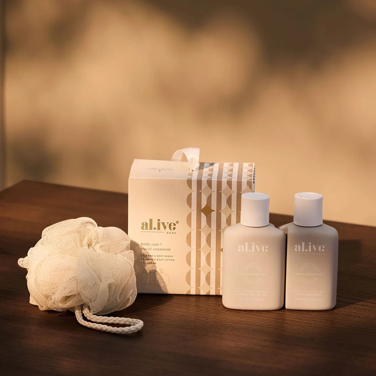 al.ive body Body Care Travel Ornament with travel bottles and loofah on a timber table
