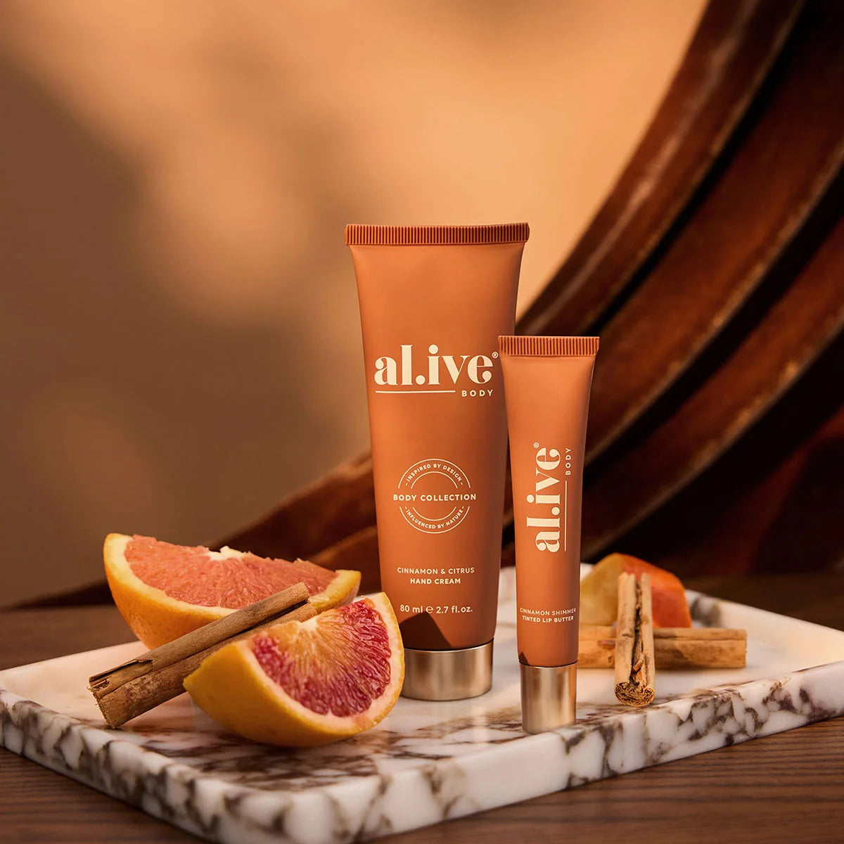 al.ive body Cinnamon & Citrus Hand Cream and Tinted Lip Butter with blood orange and cinnamon on marble