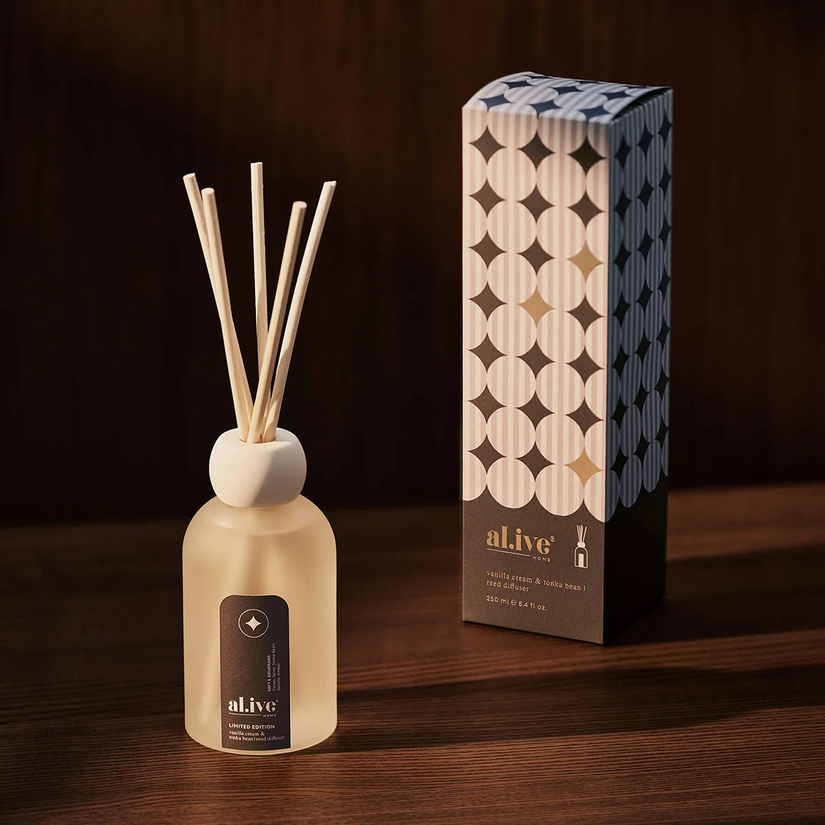 al.ive body Vanilla Cream & Tonka Bean Reed Diffuser beside its gift box on a timber table