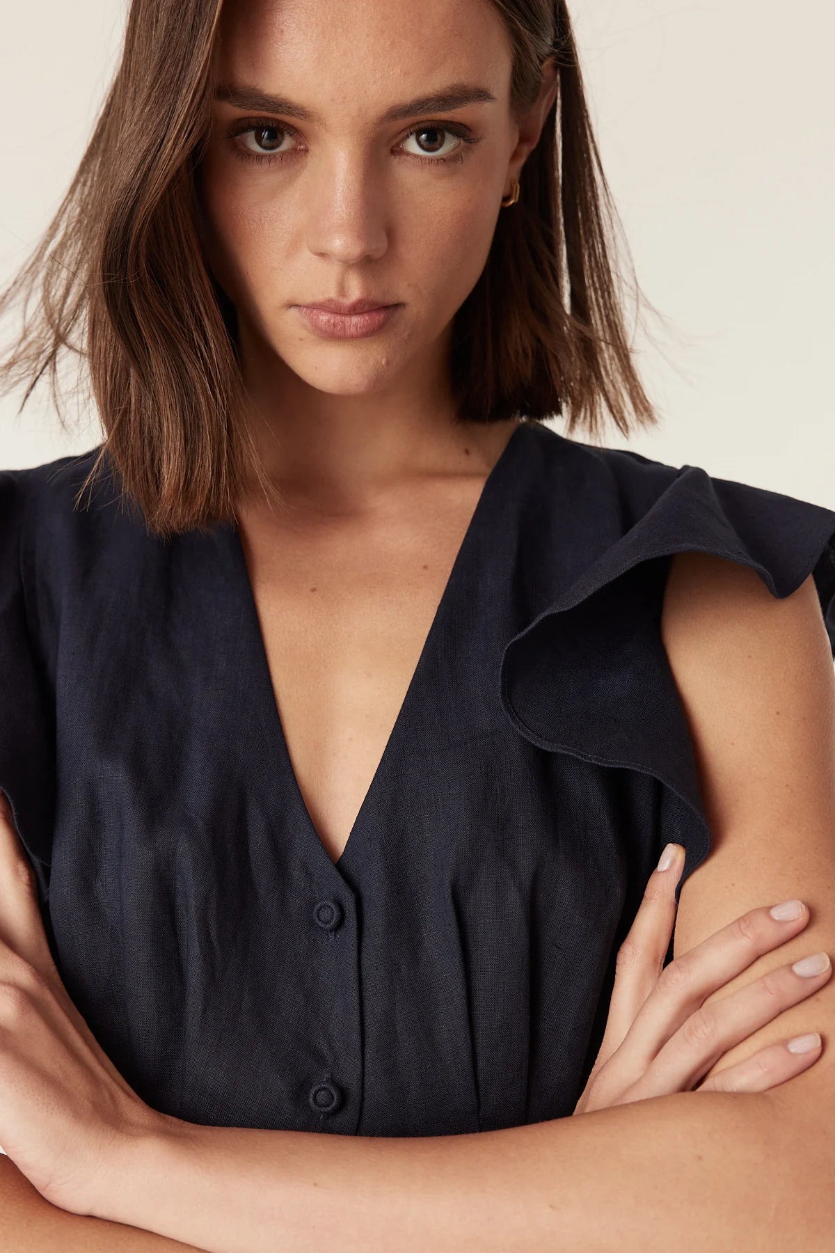 Close-up of the V-neckline and button-through bodice on the Cable Melbourne Bellevue Linen Dress in Navy, worn