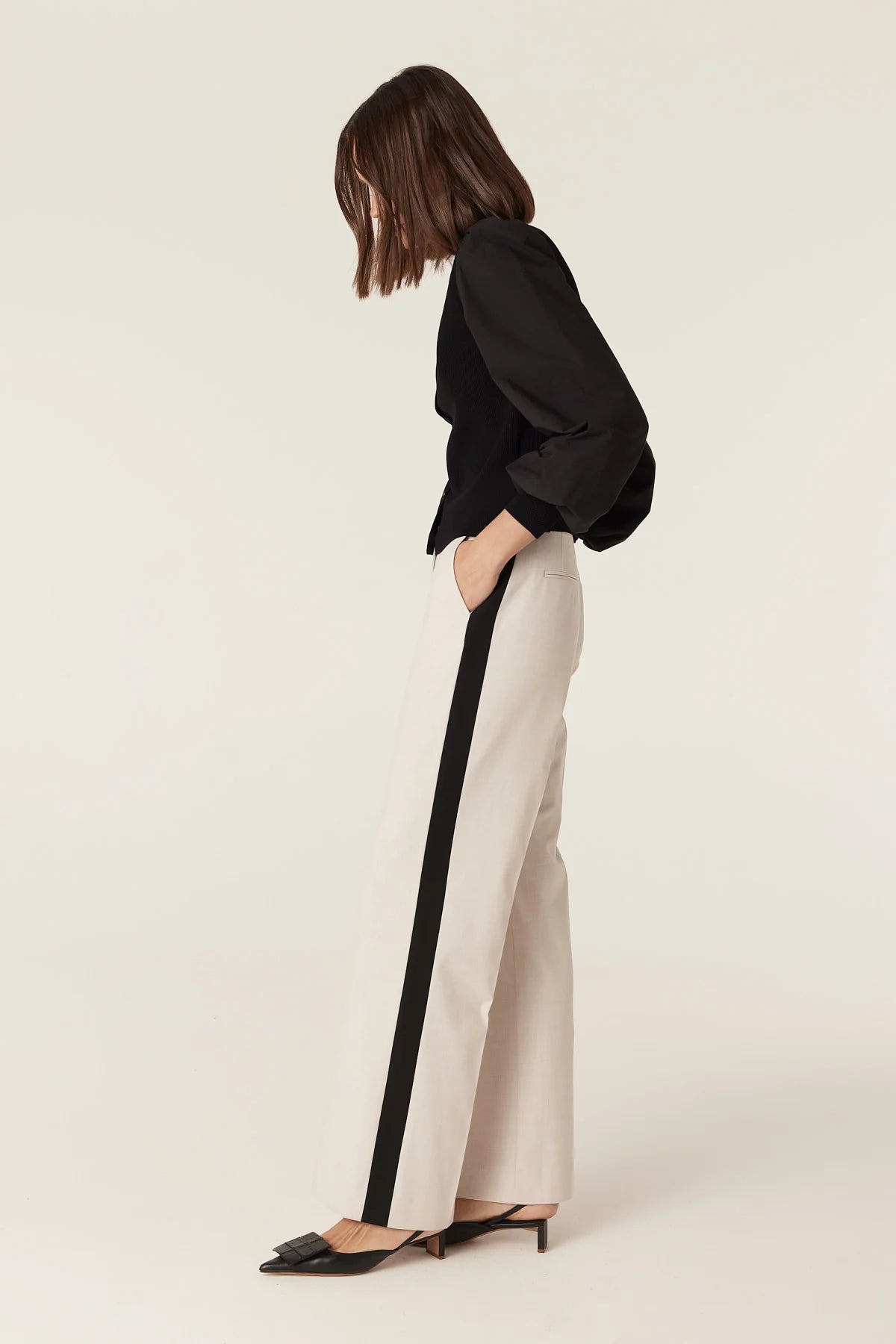 Cable Melbourne Crepe Spring Cardigan in Black paired with cream trousers, seated lifestyle shot