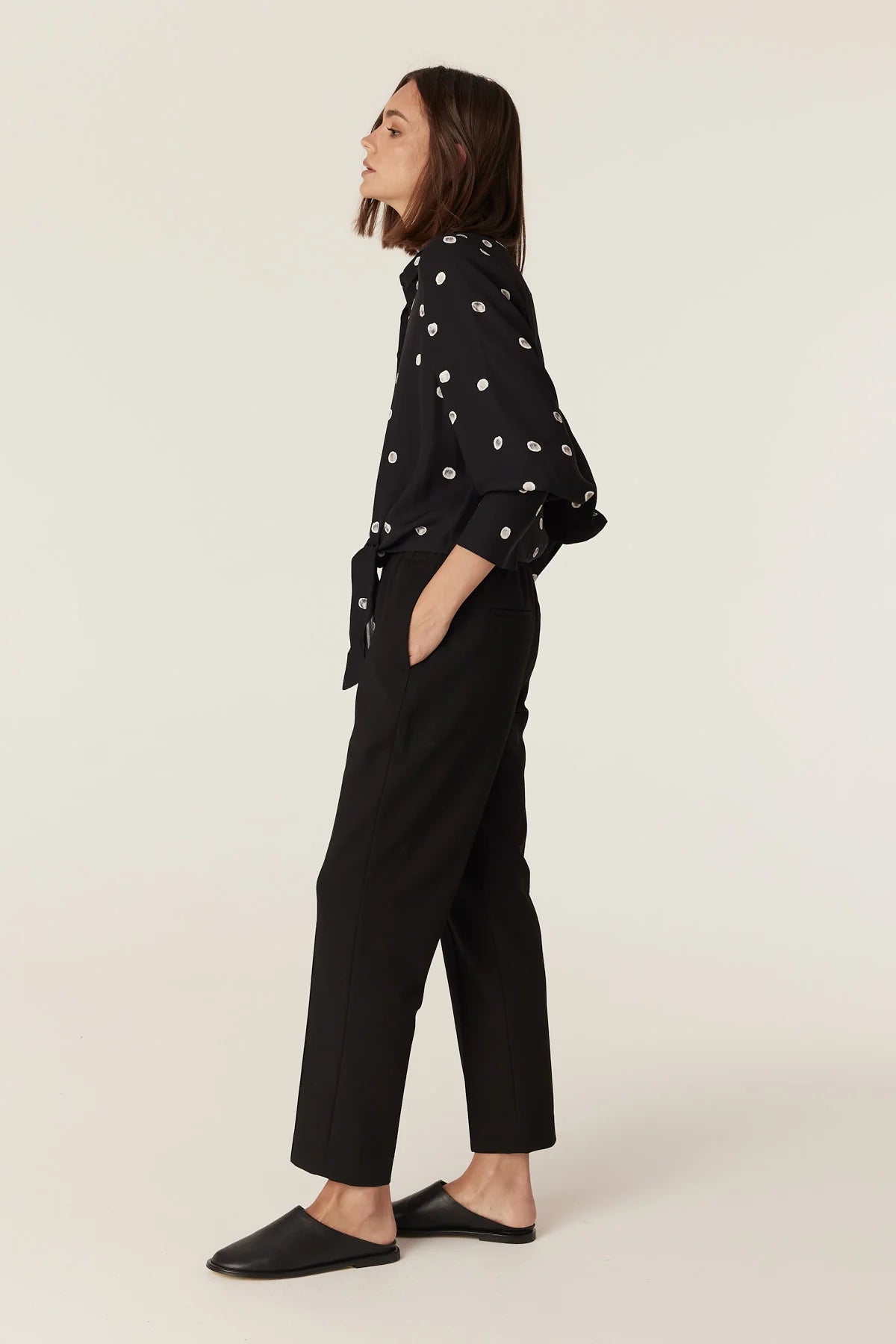 Side view of the Cable Melbourne Hepburn Blouse in Black Spot styled with tailored trousers