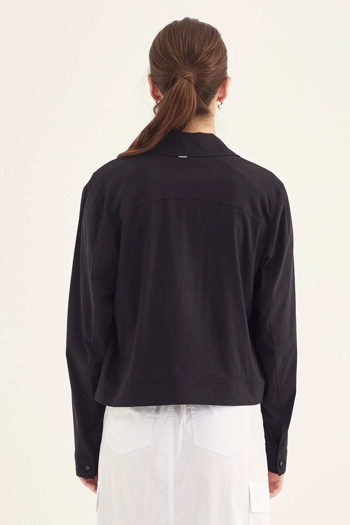 Verge Acrobat Icon Jacket in Black, worn - back with a white skirt